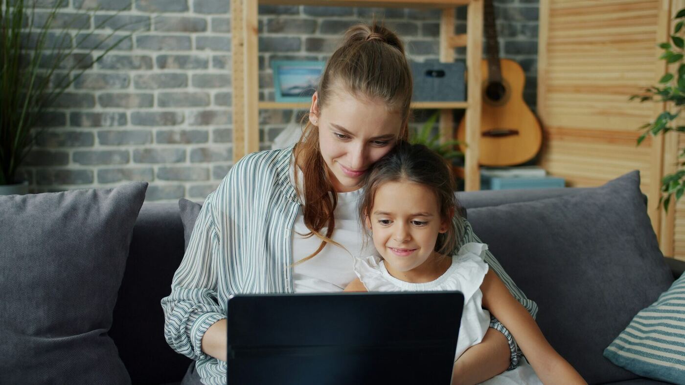 A parent and child sitting together looking at a laptop screen